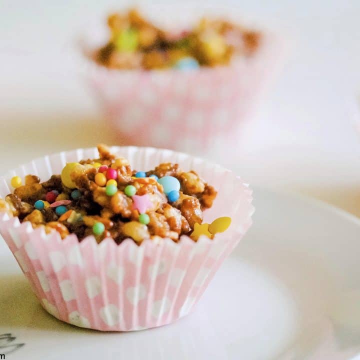 chocolate rice krispie cupcake on a plate with more cakes behind it and a white background.