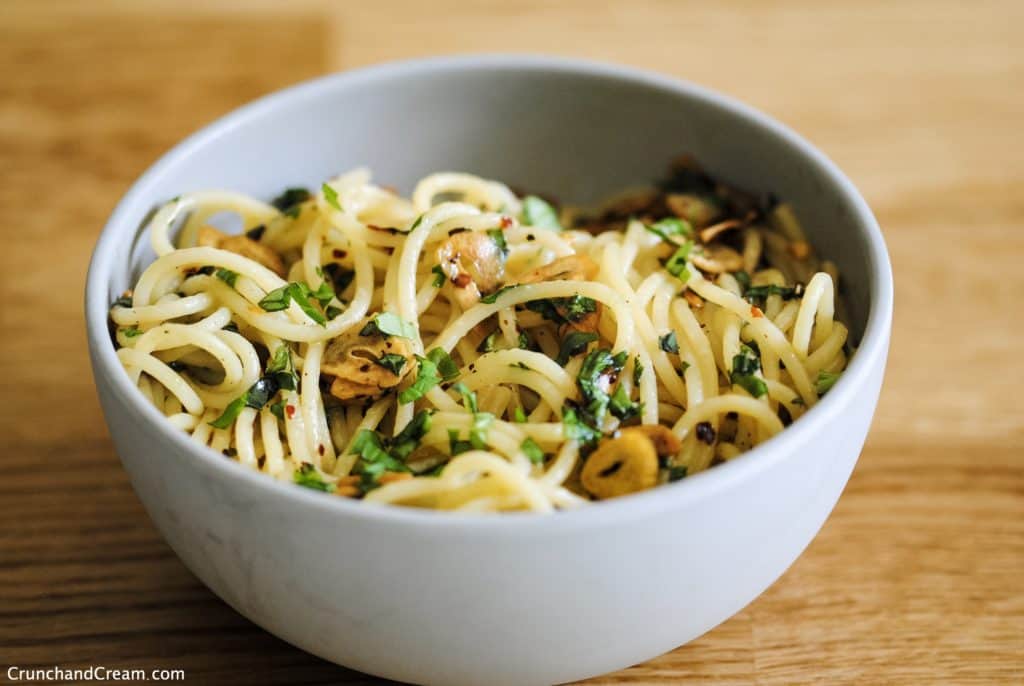 bowl of spaghetti with finely chopped fresh basil, chilli flakes, and thinly sliced garlic