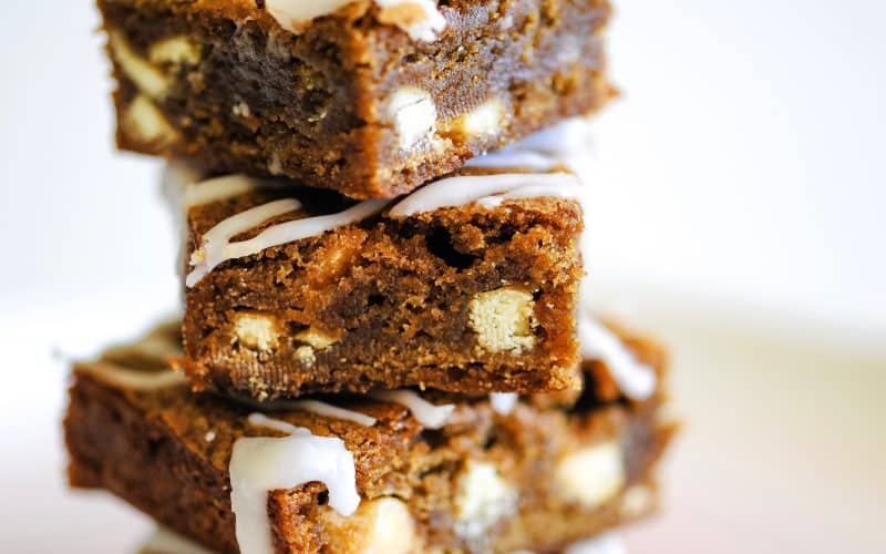 a stack of chewy white chocolate blondies drizzled with white frosting