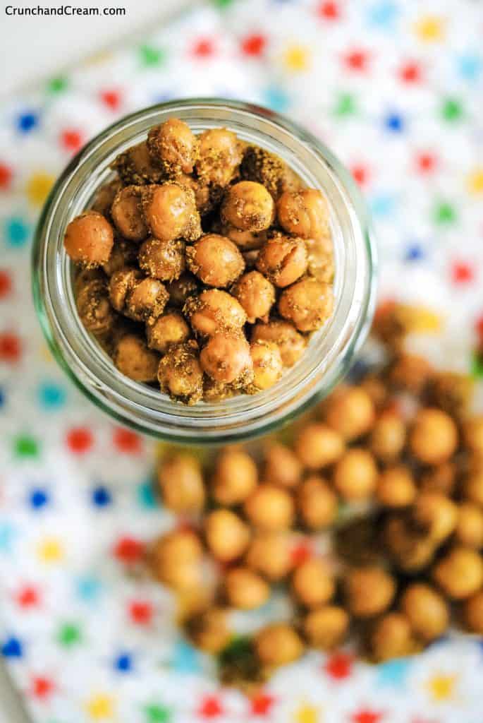 overhead of a jar of indian chickpeas on a patterned napkin scattered with more chickpeas