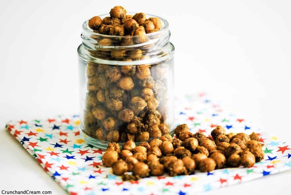 a jar of indian chickpeas on a patterned napkin scattered with more chickpeas