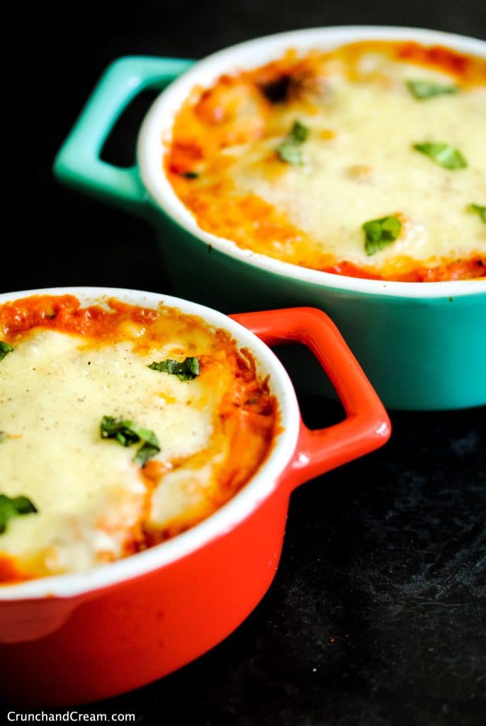 2 individual casserole dishes full of baked rice in a tomato sauce topped with melted cheese