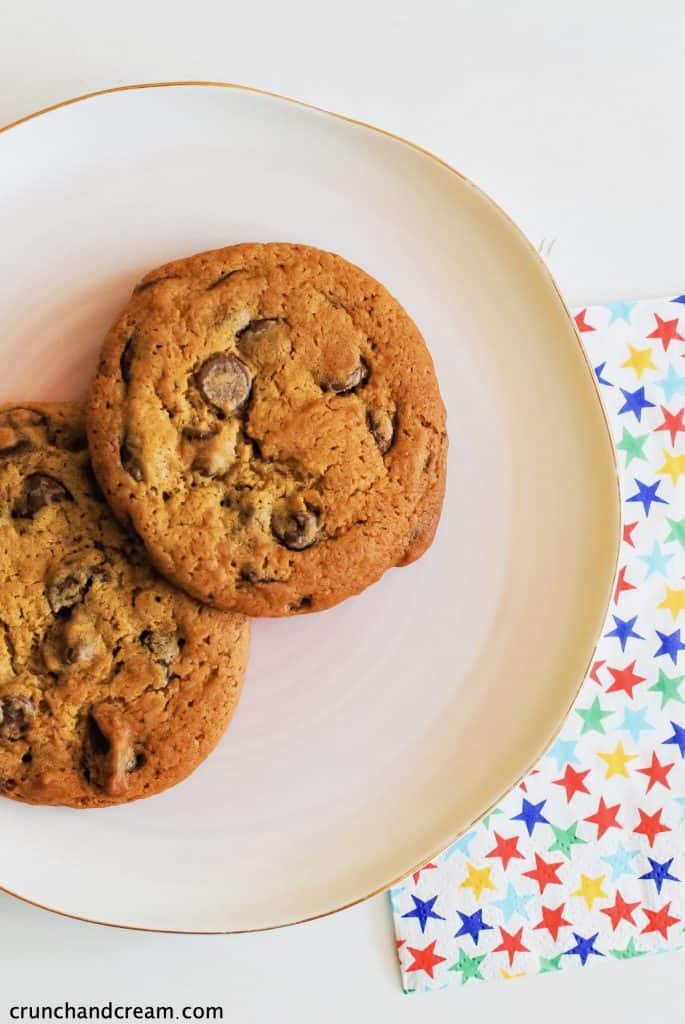 overhead of 2 chocolate chip cookies on a plate with a starry napkin