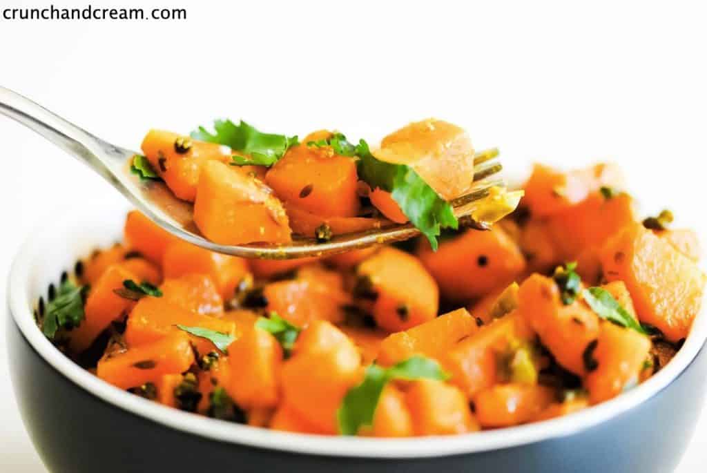 fork holding diced carrot coated with spices