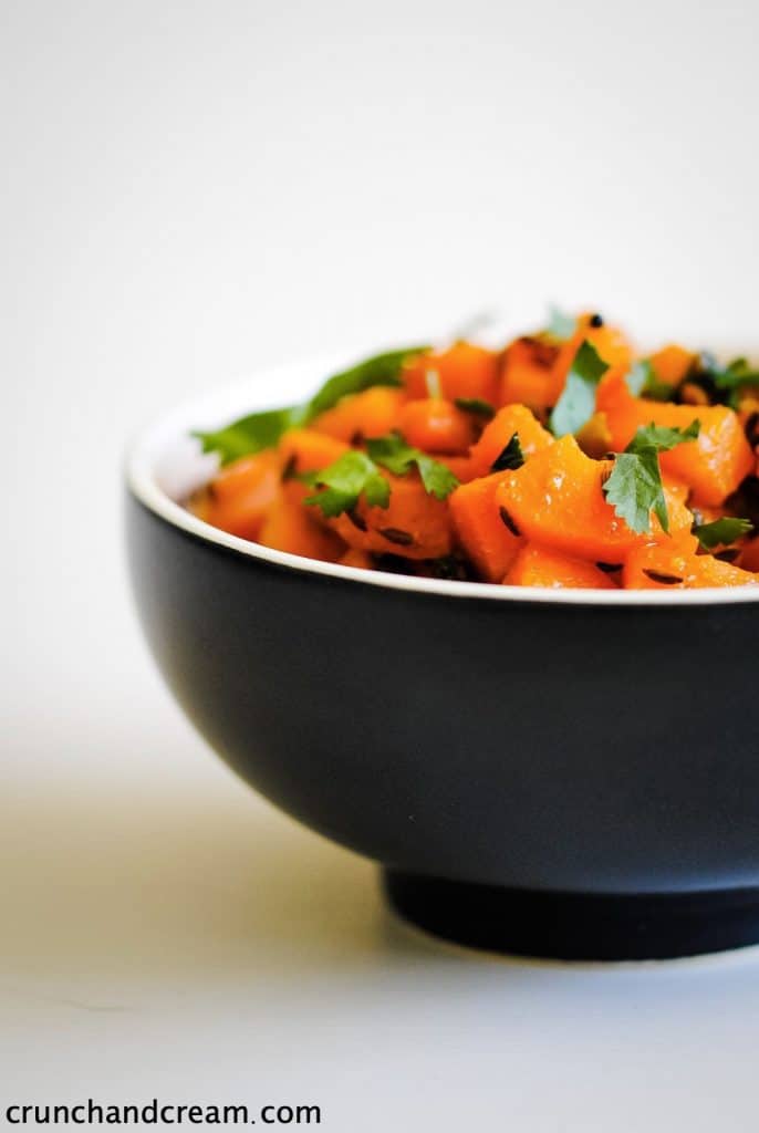 bowl of diced carrots with some fresh herbs and spices
