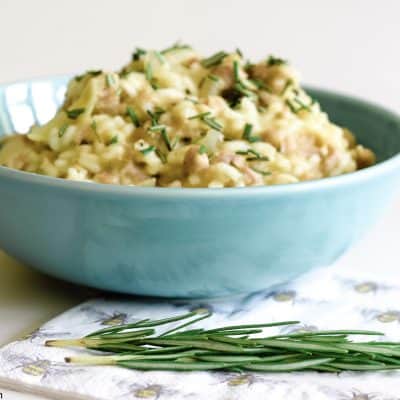 large bowl of risotto with a patterned napkin and some fresh rosemary