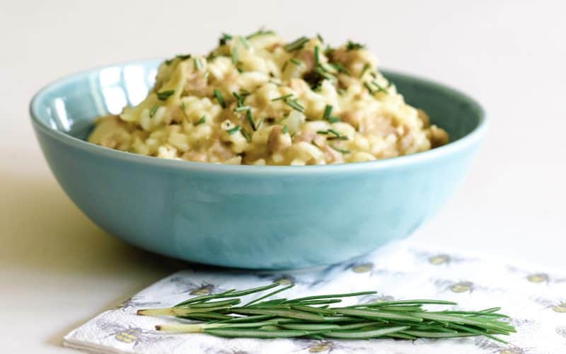large bowl of risotto with a patterned napkin and some fresh rosemary