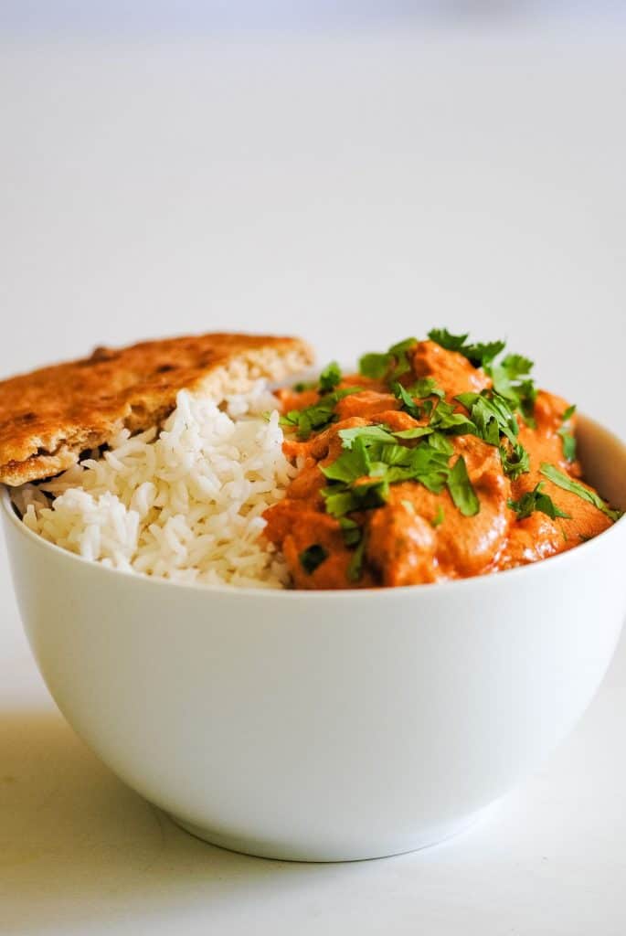 bowl of rice and orange curry sauce with a naan bread