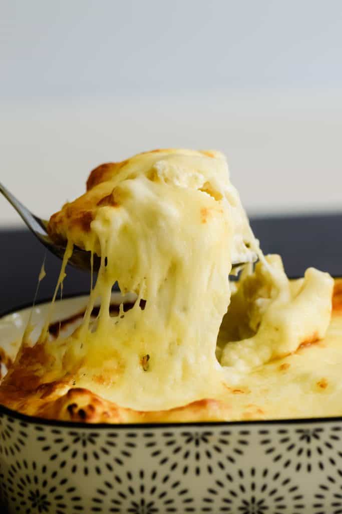 serving a portion of macaroni cheese covered in melted cheese