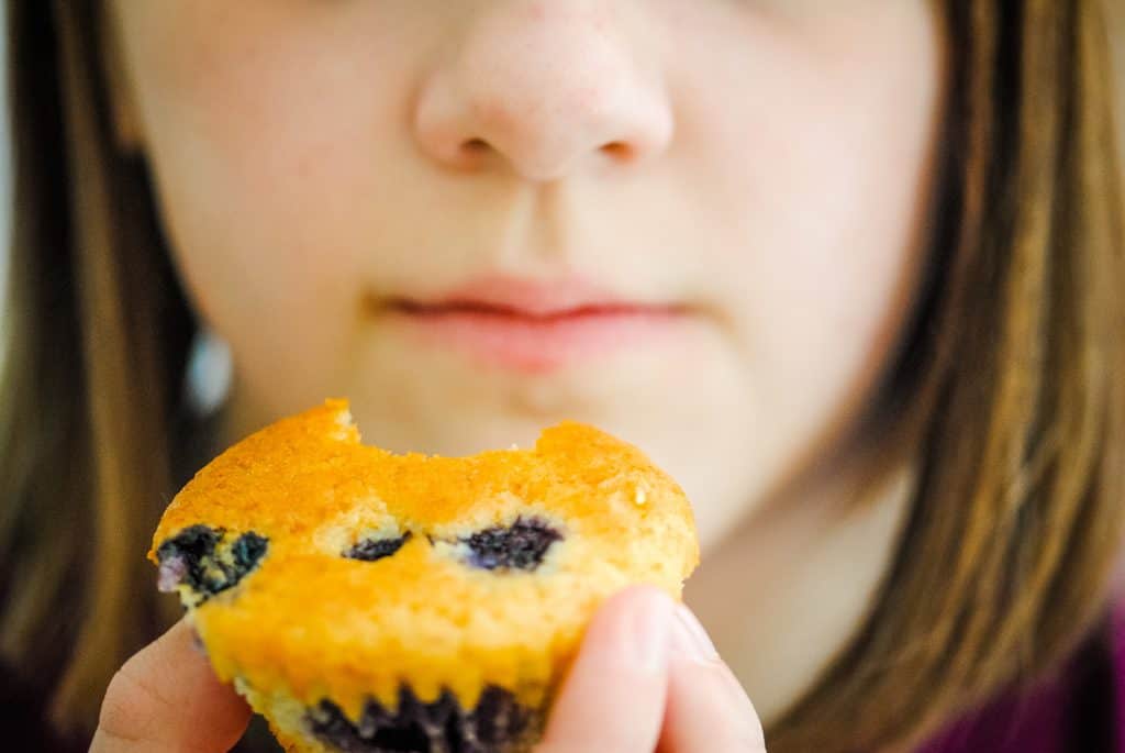 young girl eating blueberry cupcake