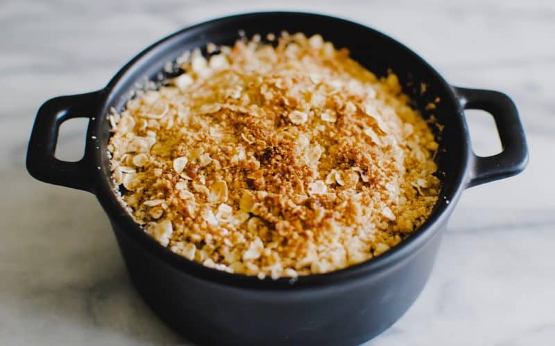a small round dish of apple crumble with a golden, crispy topping