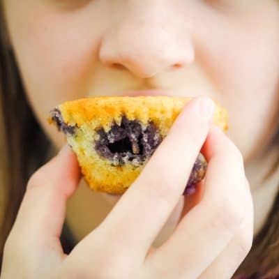 young girl eating blueberry cupcake